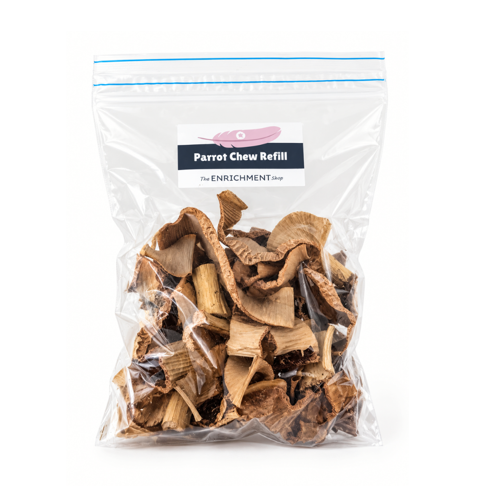 A clear plastic resealable bag filled with dried parrot chew pieces, with a printed label reading 'Parrot Chew Refill' and 'The Enrichment Shop' on a white background.